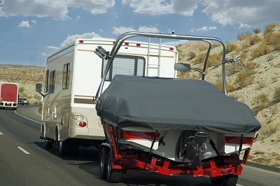 A recreational vehicle towing a boat on a road trip.